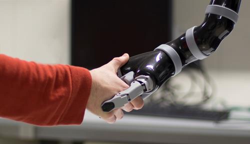 Photograph of human and robotic arms shaking hands. Scientists are devising ways for people with paralysis to control computers, robotic prosthetics and even their own limbs with their thoughts.