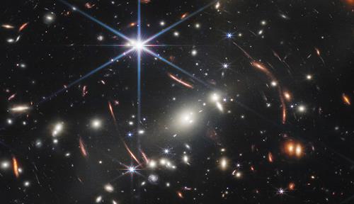 Thousands of bright galaxies are visible in the darkness of space in a processed image originally captured using a near-infrared camera focused on the galaxy cluster SMACS 0723. 