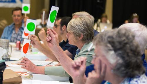 Photograph of participants voting “yes” or “no” in a deliberative process in 2014 in Oregon, where the state’s Citizens’ Initiative Review process selects a demographically balanced group of 24 voters to consider ballot measures. The result is a statement containing key facts and the best reasons to vote for or against a measure; it is distributed widely to citizens before they cast their vote. Under consideration here was Measure 90, which would have permitted open primaries (it failed).