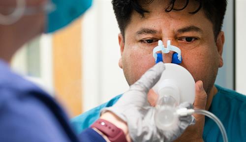 A patient breaths in through a breathing apparatus during a medical test