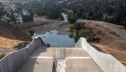 Photograph of a long concrete chute running into a reservoir that doesn’t seem to have much water in it!